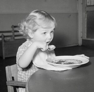 Young girl eating a bowl of soup.